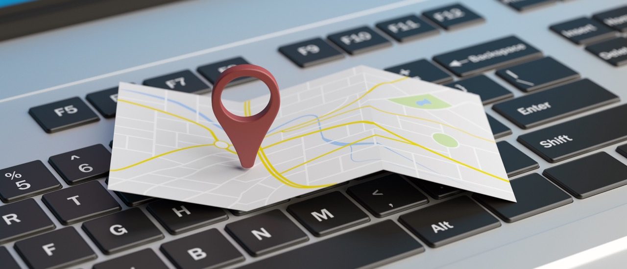 Mapa de papel com um marcador de localização apoiado sobre um teclado