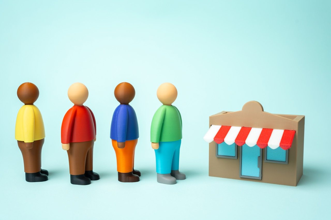 Figuras representando clientes em fila diante de uma loja em miniatura