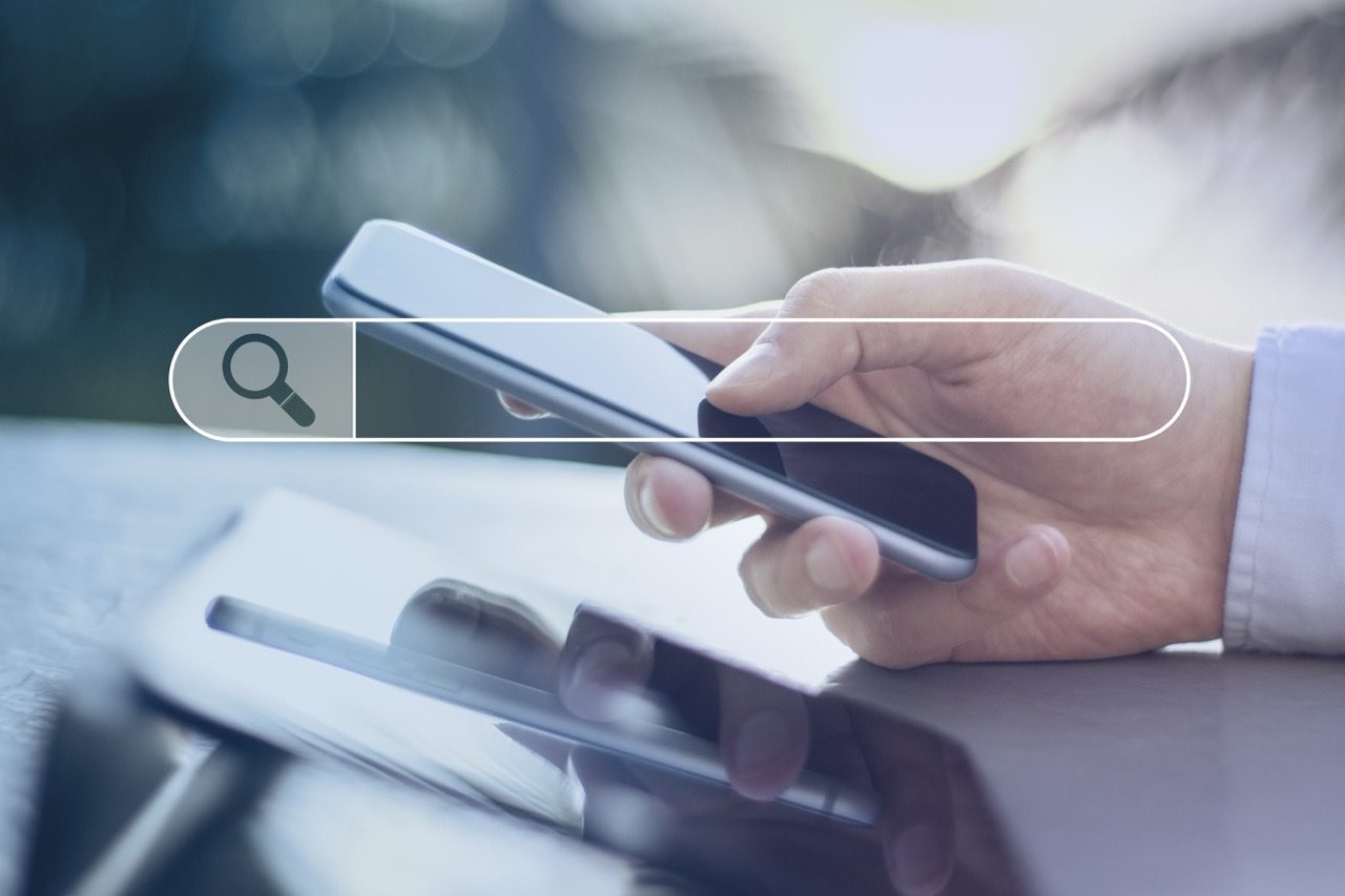 Pessoa fazendo uma busca no celular, com a barra de pesquisa em destaque