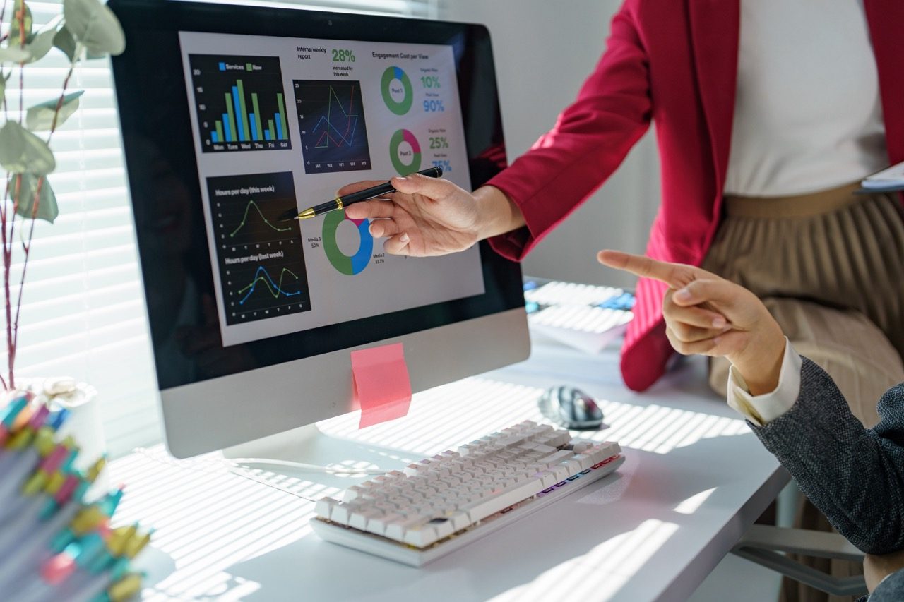 Duas profissionais analisando painéis de desempenho em um monitor